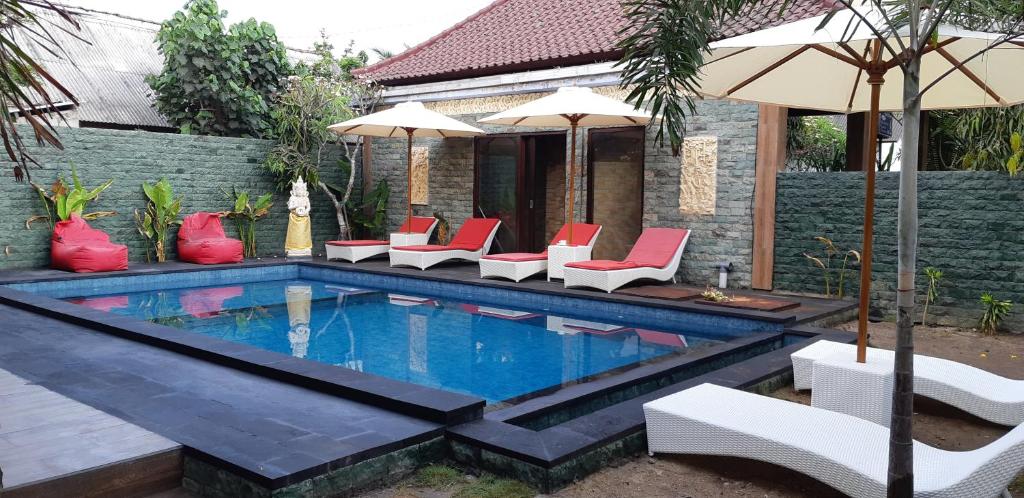 uma piscina com cadeiras vermelhas e guarda-sóis em Bunutbali Villas88 em Nusa Lembongan
