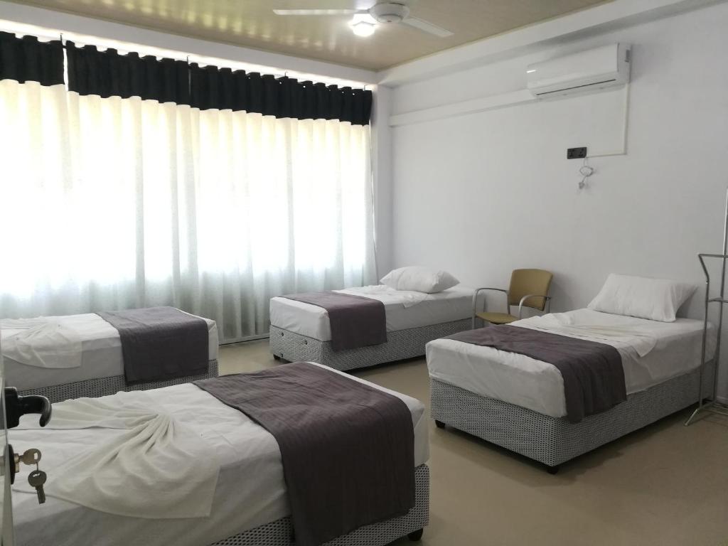Habitación con 3 camas y ventana en Thilini Hotel Apartment en Ratnapura