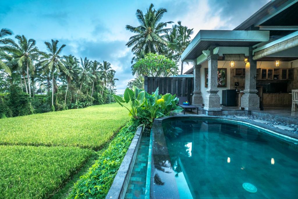a house with a swimming pool in front of a yard at Villa Kirani Ubud by Mahaputra-CHSE Certified in Ubud