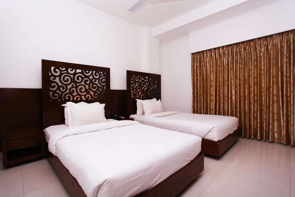two beds in a hotel room with white sheets at La Vista Hotel in Sylhet