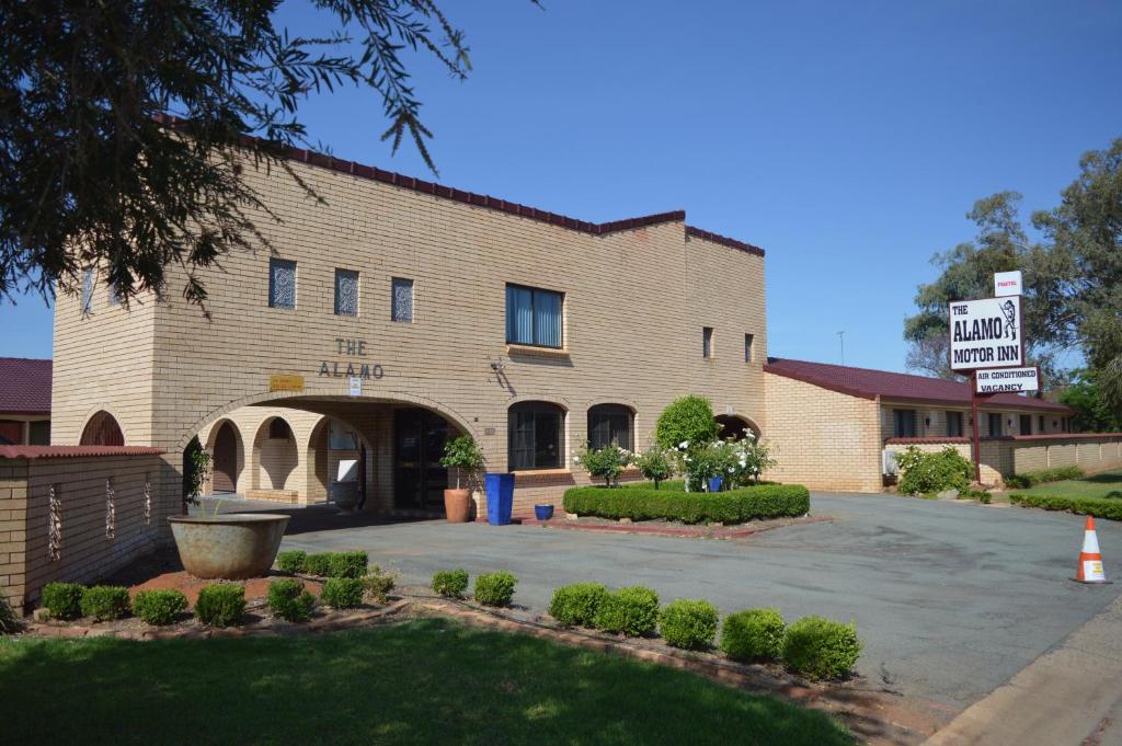 un grande edificio in mattoni con un cartello di fronte di Alamo Motor Inn a Nyngan