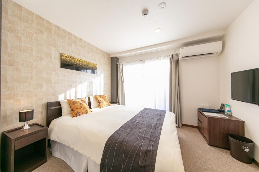 1 dormitorio con 1 cama grande y TV en Komachi Hotel Nipponbashi, en Osaka