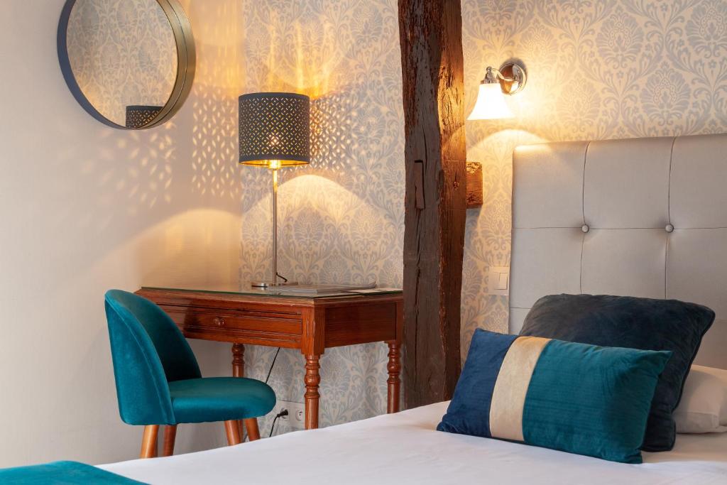 a bedroom with a bed and a desk and a chair at Hotel Mirabeau in Tours