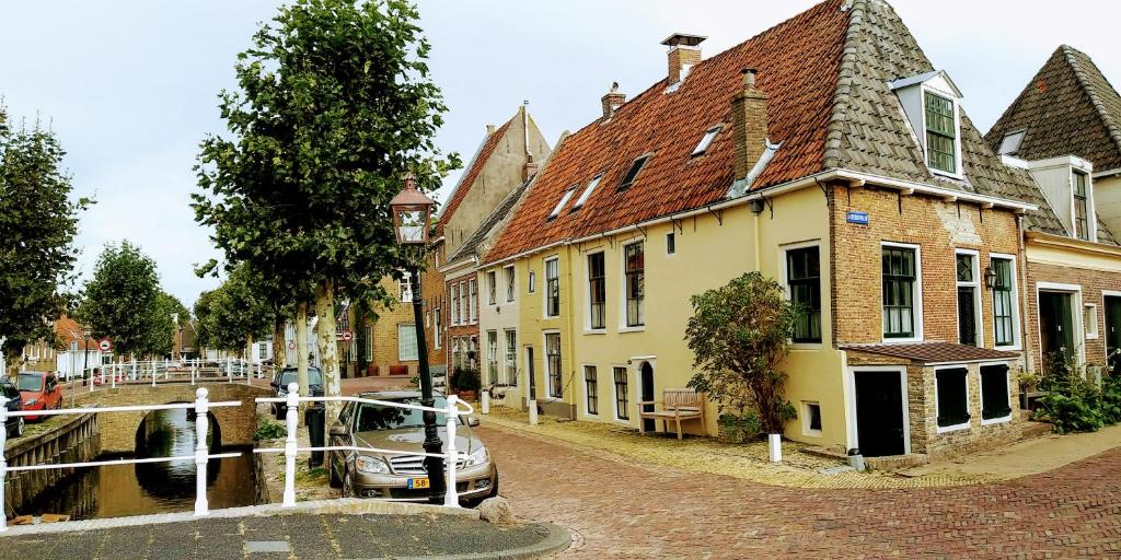 a street with a house and a boat in a canal at Het Goede Leven in Harlingen