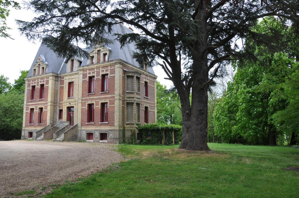 een groot huis met een boom ervoor bij Château De La Croix Bizet in Moulineaux