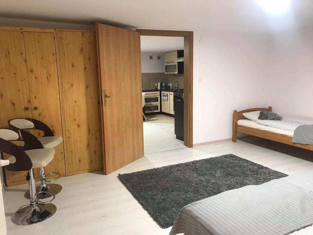 a bedroom with a bed and a chair and a kitchen at Przytulne mieszkanie w urokliwej okolicy in Chodzież