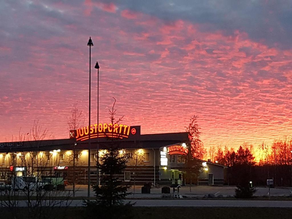a gas station with a neon sign at sunset at Hotelli Kärsämäki in Kärsämäki