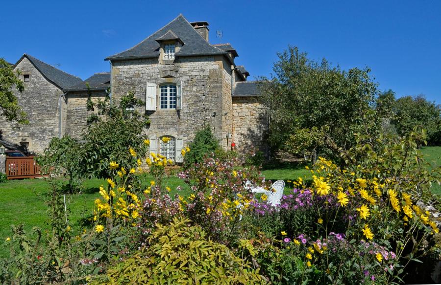 uma antiga casa de pedra com um jardim de flores em LES HAUTS DU CAUSSE em Grand-Mas