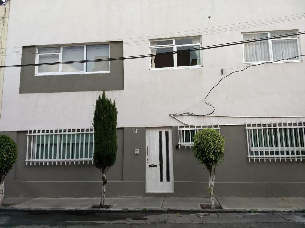 uma casa branca com árvores em frente em Departamentos Amueblados la Condesa em Cidade do México