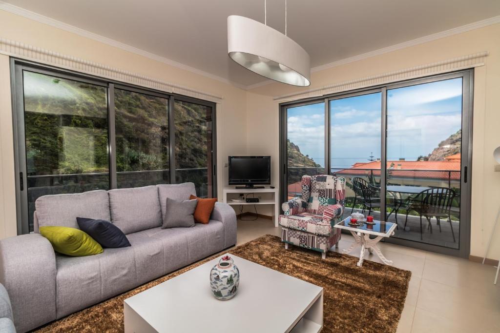 a living room with a couch and a large window at Pink House - Tabua (Ribeira Brava) in Ribeira Brava