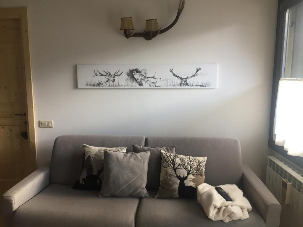 eine graue Couch mit Kissen und ein Bild an der Wand in der Unterkunft Rustico in Temù
