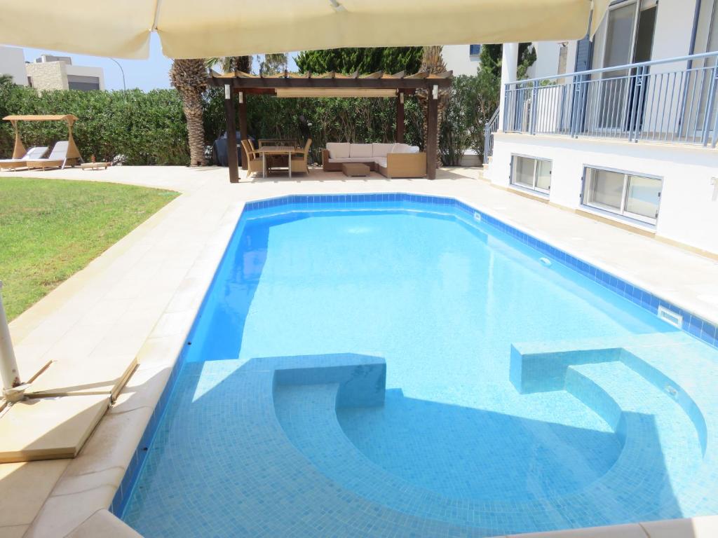 ein großer blauer Pool mit Sonnenschirm in der Unterkunft Villa Victoria in Paphos City