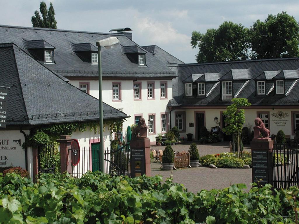 a large white house with a gate in a garden at Residenz Weingut Schloss Reinhartshausen in Eltville