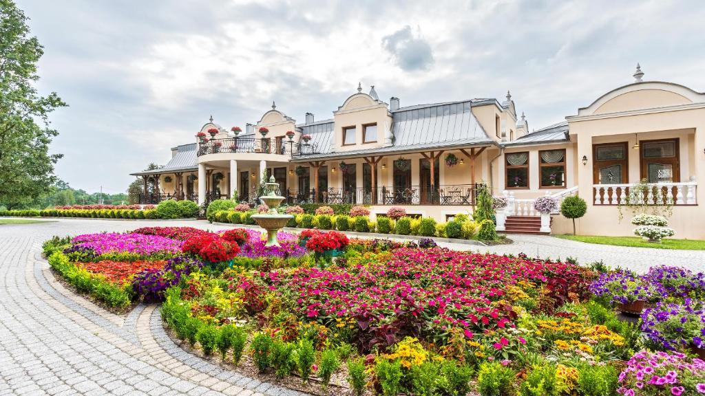 a garden in front of a building with flowers at Leśna Perła - Restauracja i Pokoje Hotelowe in Rudzinitz