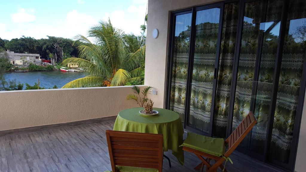 a table and chairs on a balcony with a view of a river at Riverside Holiday Home in Grande Rivière Sud Est