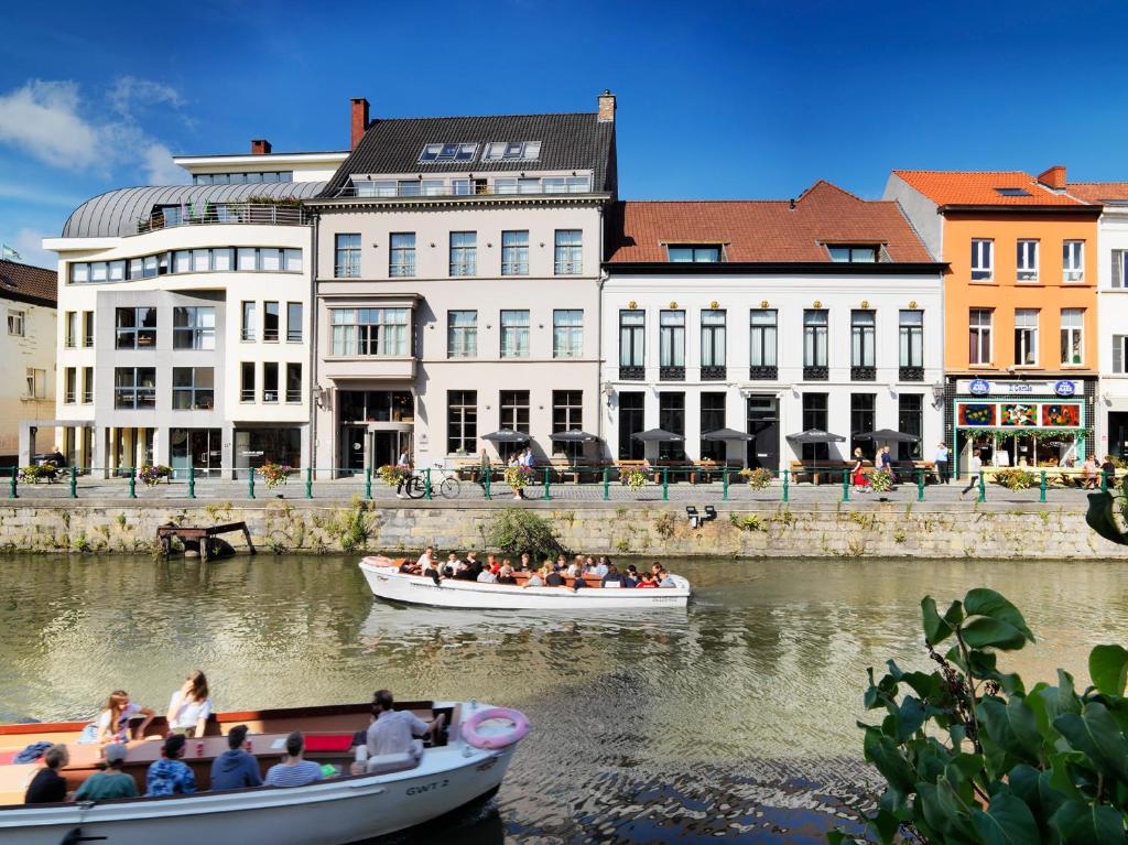 people in boats on a river in front of buildings at Hotel Harmony in Ghent