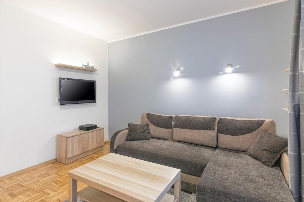 uma sala de estar com um sofá e uma televisão em TriApart Cozy em Gdansk