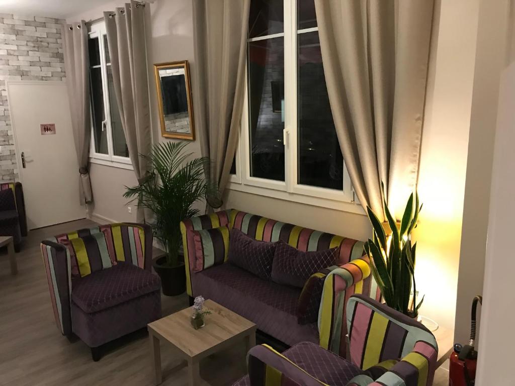 a living room with a couch and chairs and windows at HÔTEL LES IRIS in Les Andelys