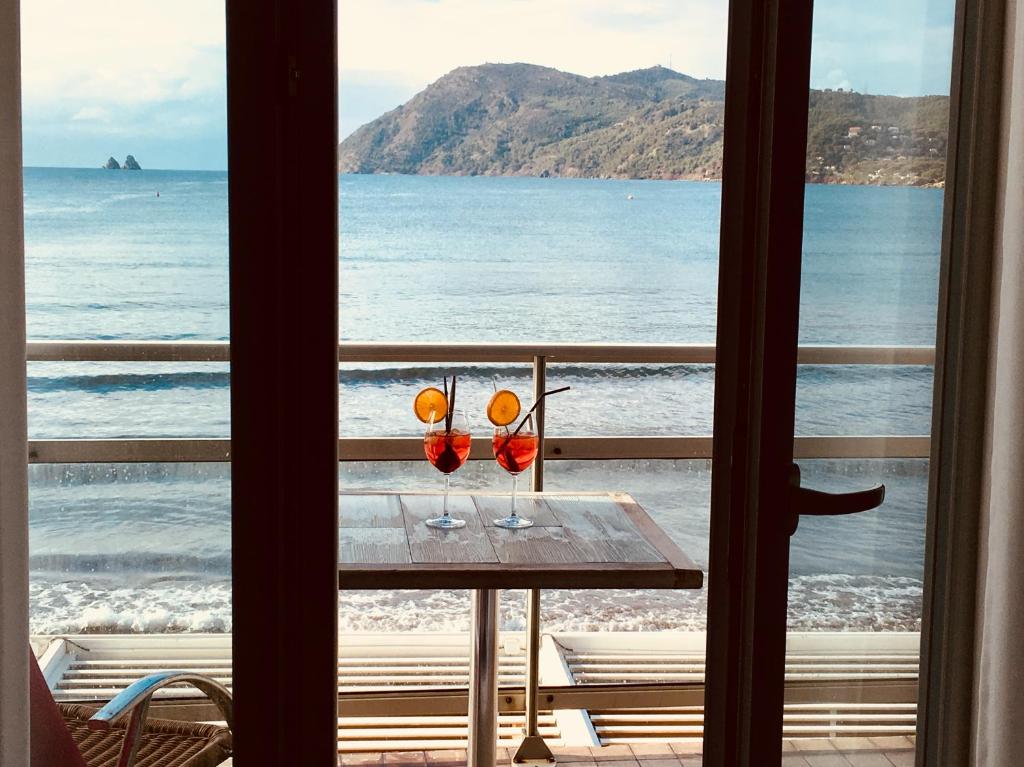 a table with two glasses on a balcony with the ocean at Le Cannier Hotel in La Seyne-sur-Mer