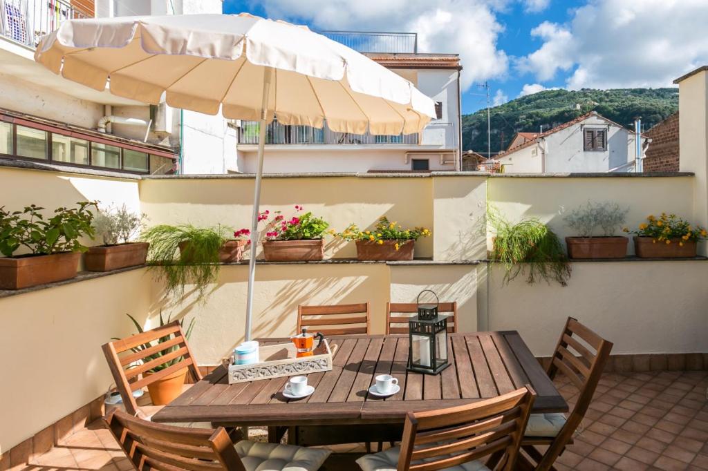 einen Holztisch mit Sonnenschirm auf dem Balkon in der Unterkunft Terrazza Felicienne in Sorrent