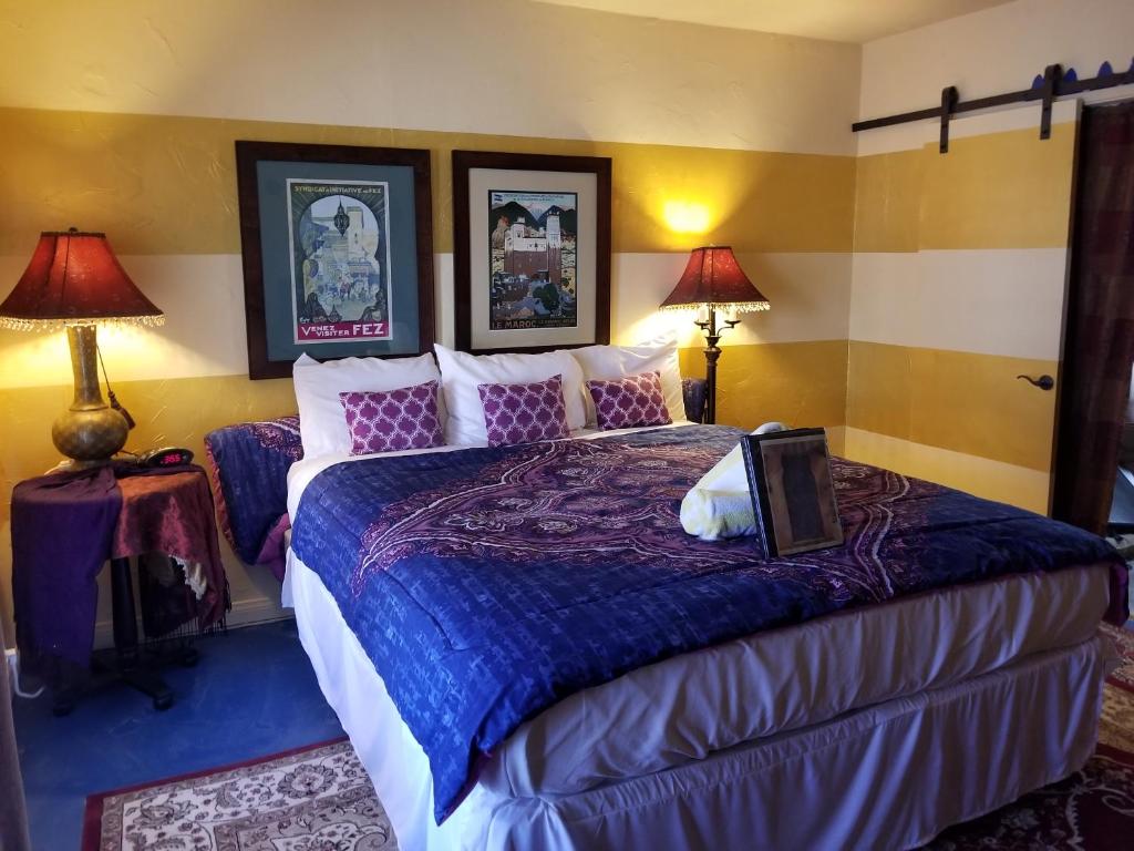 a bedroom with a large bed with purple sheets and pillows at El Morocco Inn & Spa in Desert Hot Springs