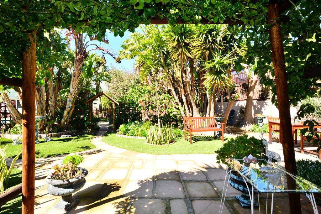 a garden with a bench and trees and grass at Secret Garden Guesthouse in Bloubergstrand