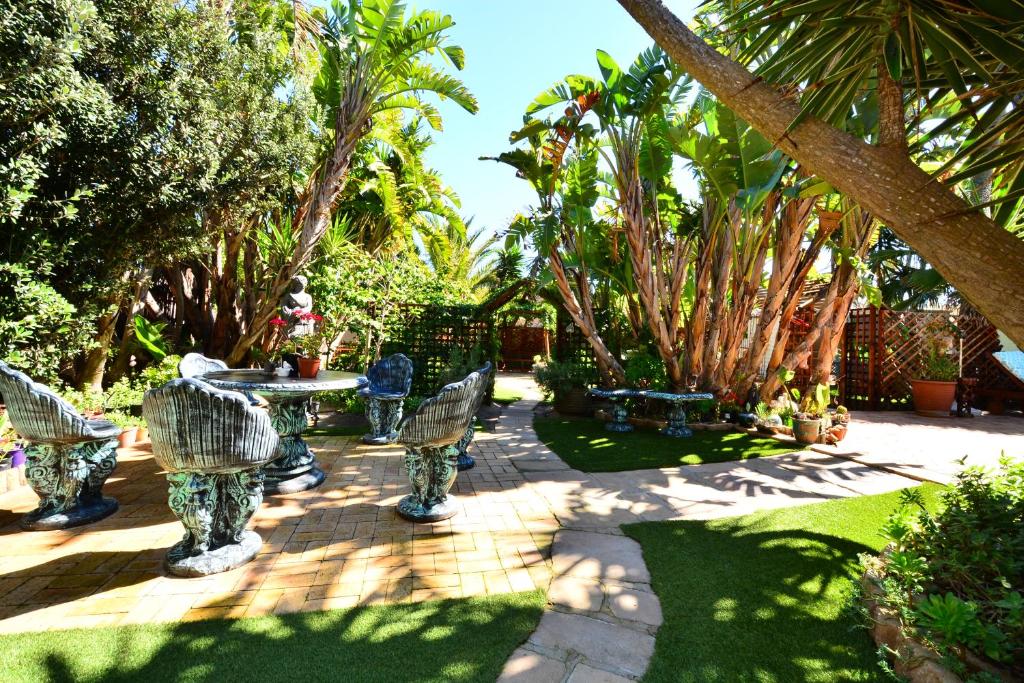 a patio with chairs and a table and trees at Secret Garden Guesthouse in Bloubergstrand