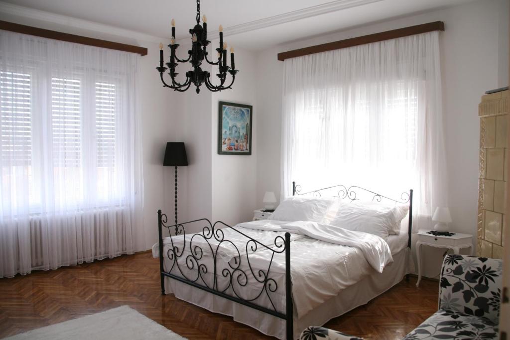 a bedroom with a bed with white sheets and a chandelier at Apartment Kalina in Novi Sad