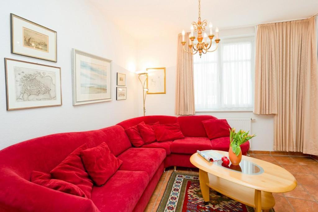 ein rotes Sofa im Wohnzimmer mit einem Tisch in der Unterkunft Villa Hildegard Appartement Nr. 1 in Binz