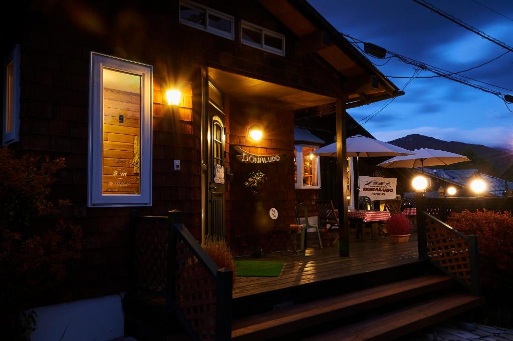 een huis met een veranda 's nachts met een paraplu bij Lake village donaludo Pension in Kitashiobara