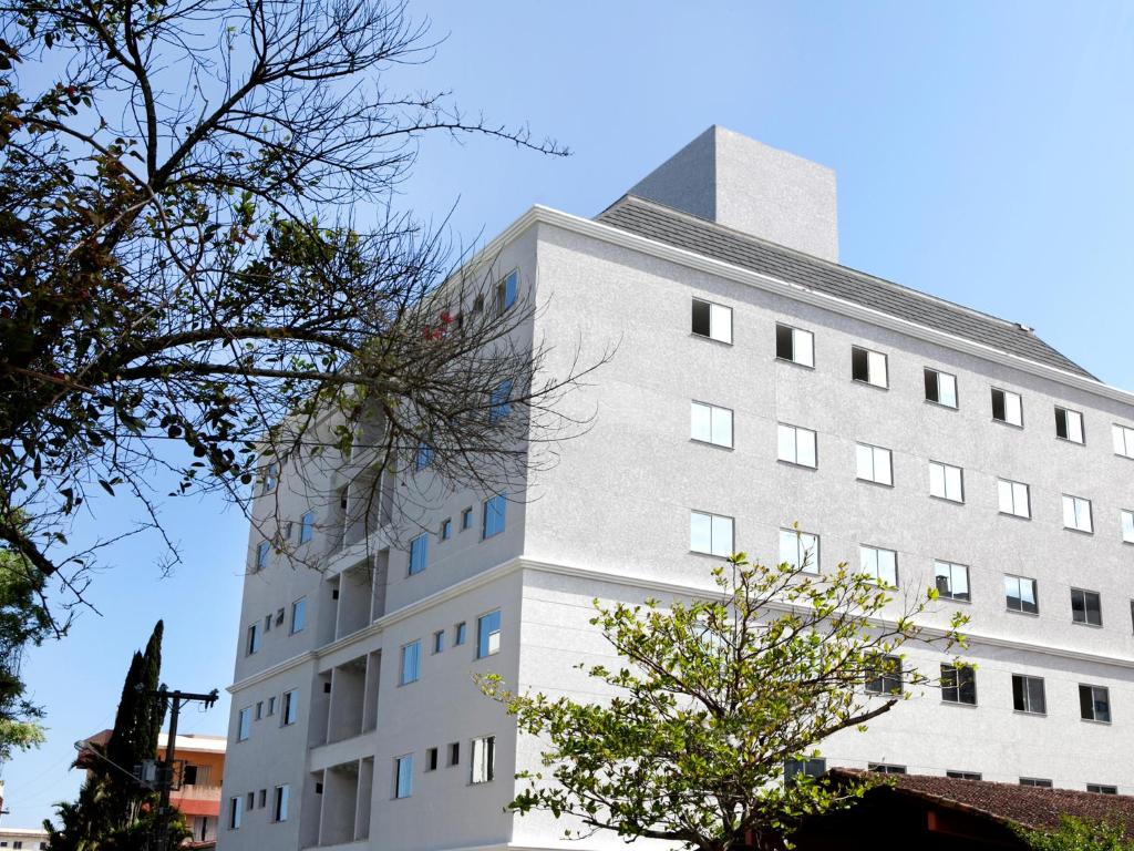 um edifício branco alto com janelas azuis em Al Mare Hotel em Florianópolis