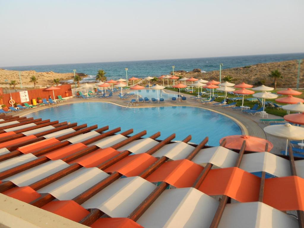 a view of a swimming pool with umbrellas and the ocean at Aktea Beach Village in Ayia Napa