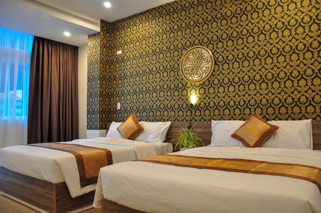 a hotel room with two beds and a wall at Nice Hue Hotel in Hue