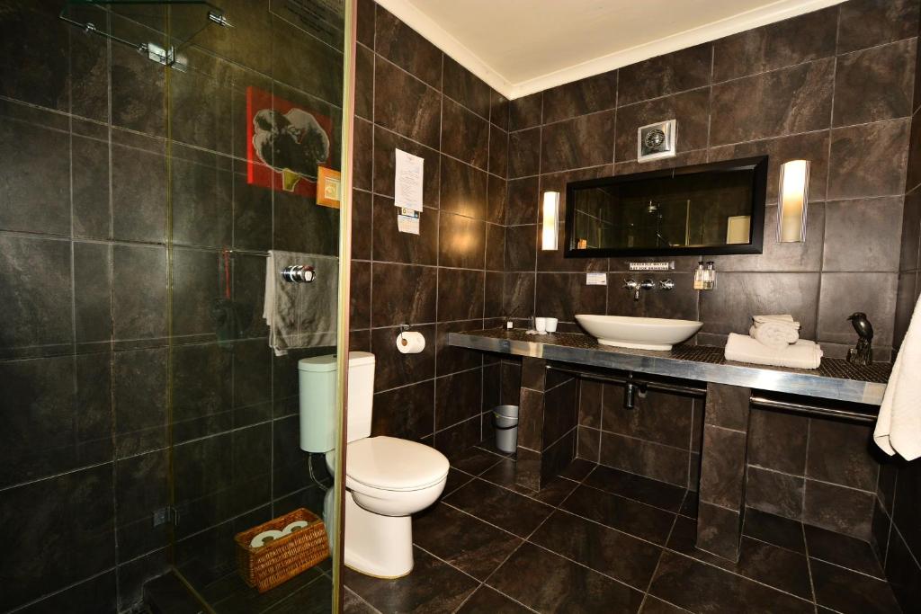 a bathroom with a toilet and a sink at Secret Garden Guesthouse in Bloubergstrand