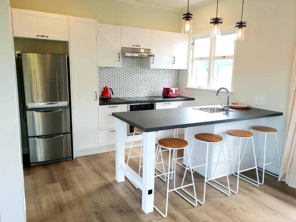 a kitchen with a sink and a counter with stools at Central Rotorua Beauty in Rotorua