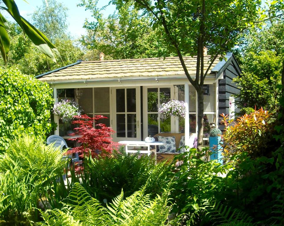 una pequeña casa con una mesa en un jardín en B&B Het Tuinhuisje en Enschede