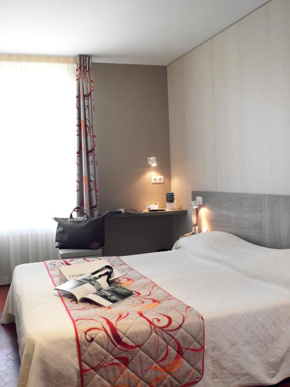 Postel nebo postele na pokoji v ubytování Brit Hotel Confort Le Revest Sainte-Maxime