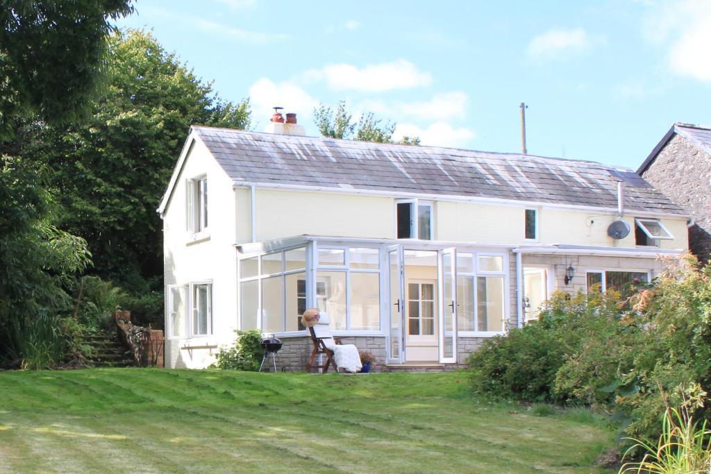 une maison blanche avec un chien assis devant elle dans l'établissement Silhouette Cottage, à Coleford