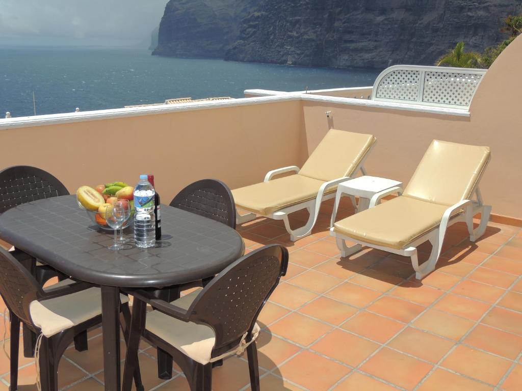 a table and chairs on a balcony with a table and drinks at Romantic Retreat with Marine View in Acantilado de los Gigantes