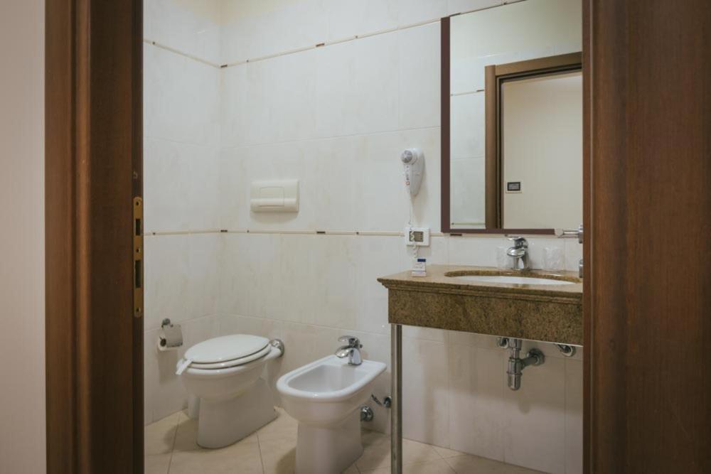 a bathroom with a toilet and a sink and a mirror at Hotel Costa Azul in Balestrate