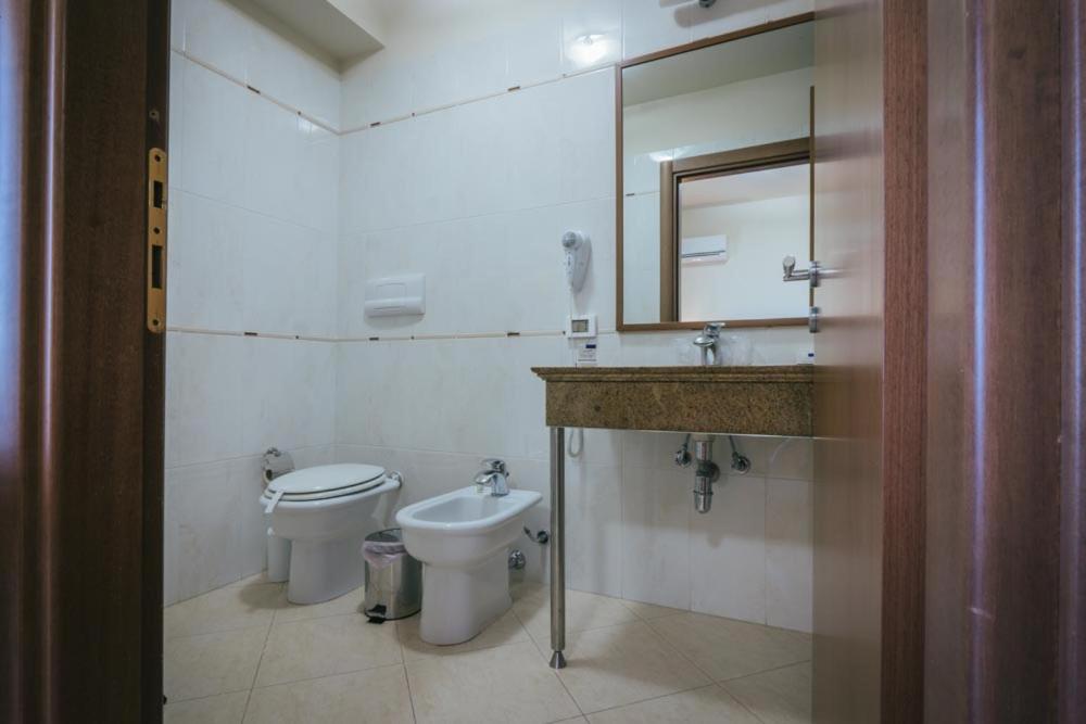 a bathroom with a toilet and a sink and a mirror at Hotel Costa Azul in Balestrate