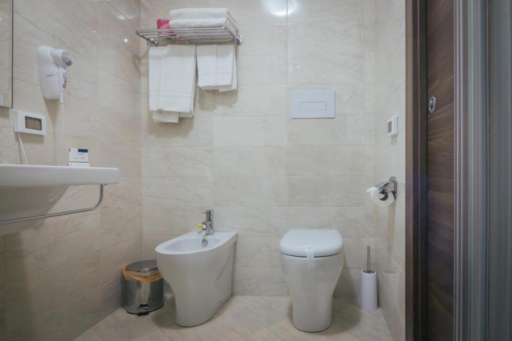 a white bathroom with a toilet and a sink at Hotel Costa Azul in Balestrate