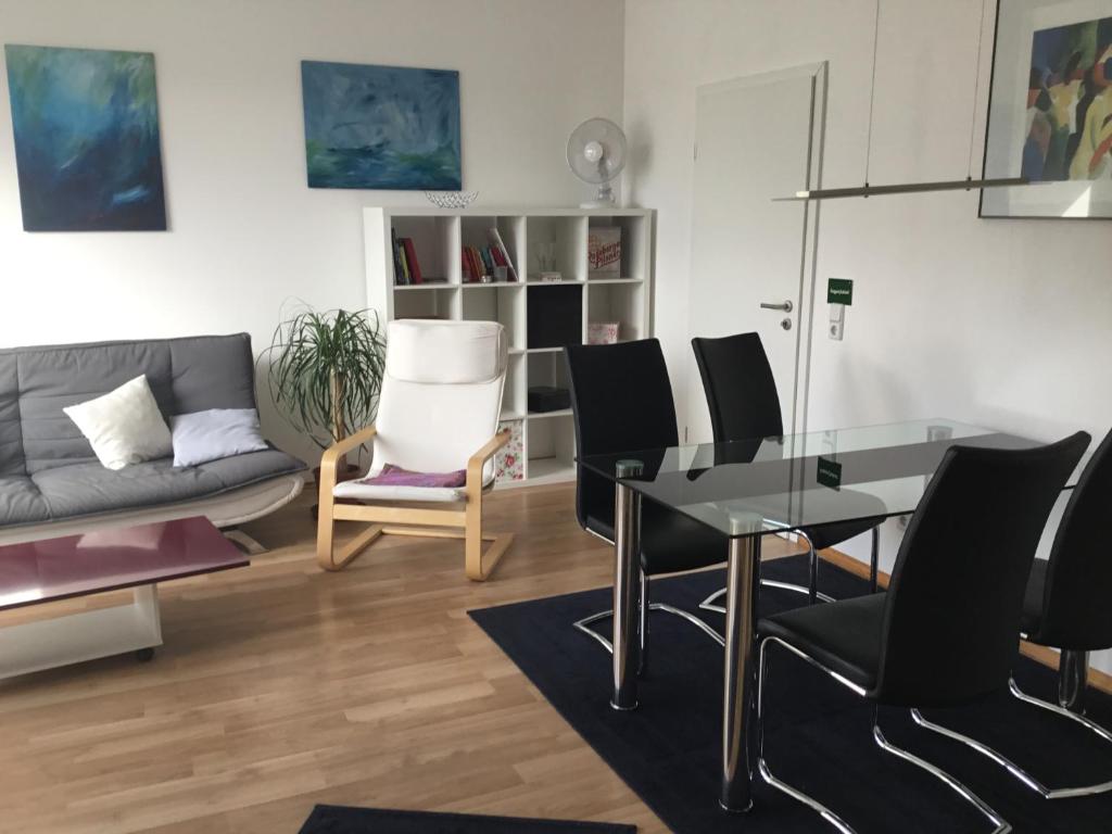 uma sala de estar com uma mesa de vidro e cadeiras pretas em Fewo, 55 qm, voll ausgestattet, mit Süd-Loggia, Nähe Völkerschlachtdenkmal em Leipzig