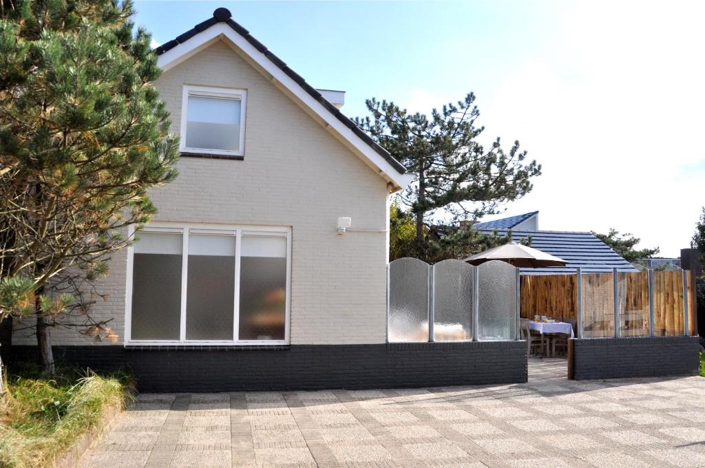 une maison avec une clôture devant elle dans l'établissement Beachhouse Bosweg, à Noordwijk aan Zee