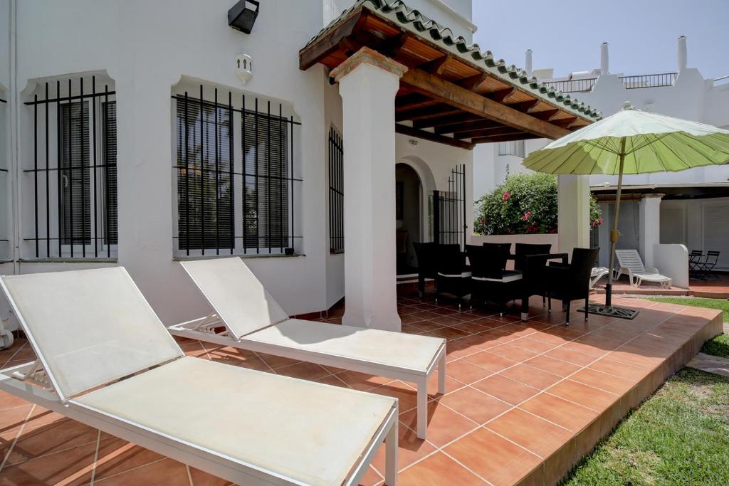 マルベーリャにある3 bed Modern House Marbella - Direct Pool Accessのパティオ(白い椅子、テーブル、パラソル付)