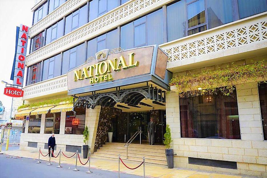 Um homem está à porta de um hotel. em National Hotel - Jerusalem em Jerusalém