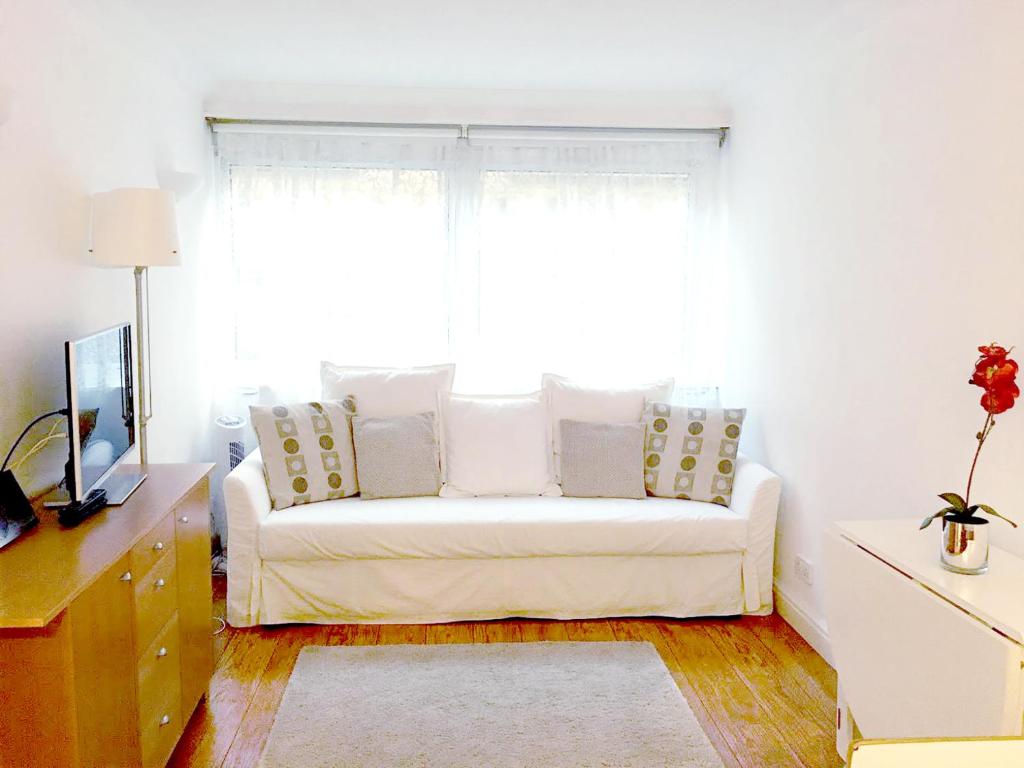 a living room with a white couch in front of a window at Elegant Very Central: Fitzrovia W1. King Bed, Wifi in London