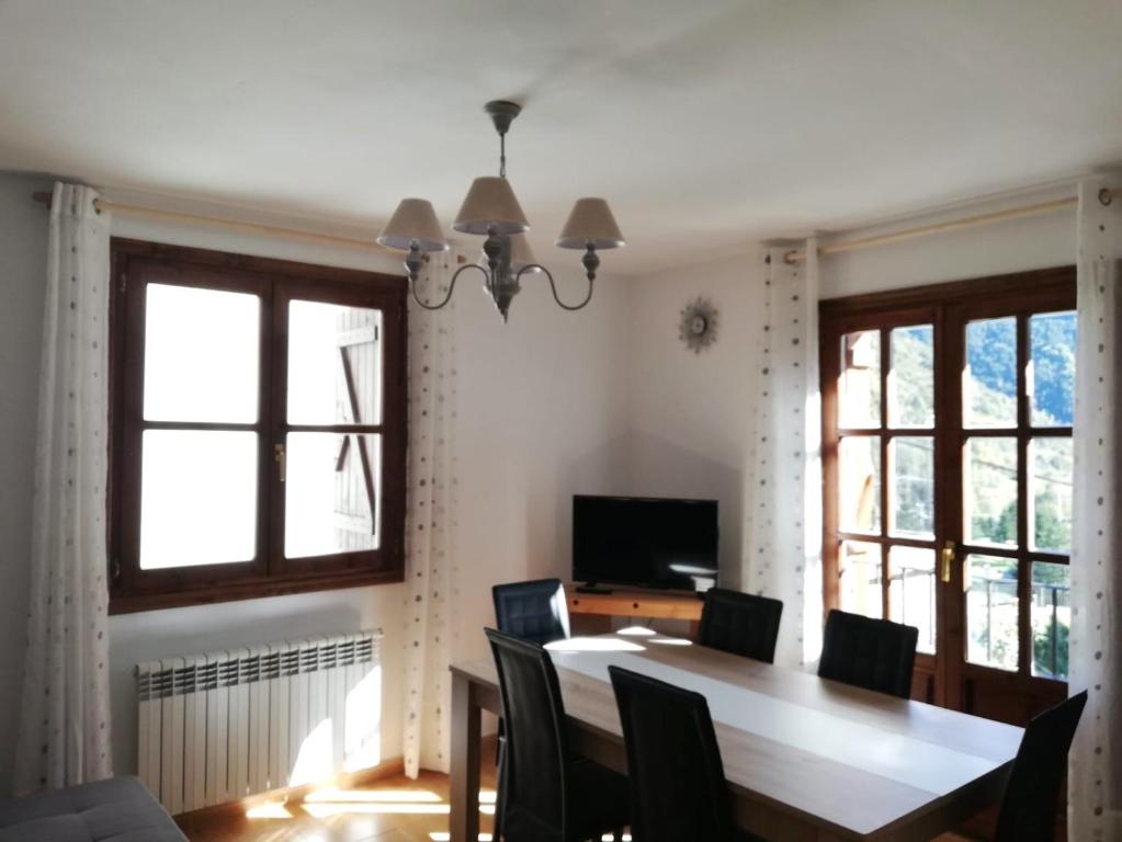 a dining room with a table and chairs and windows at Edelweiss in Bielsa