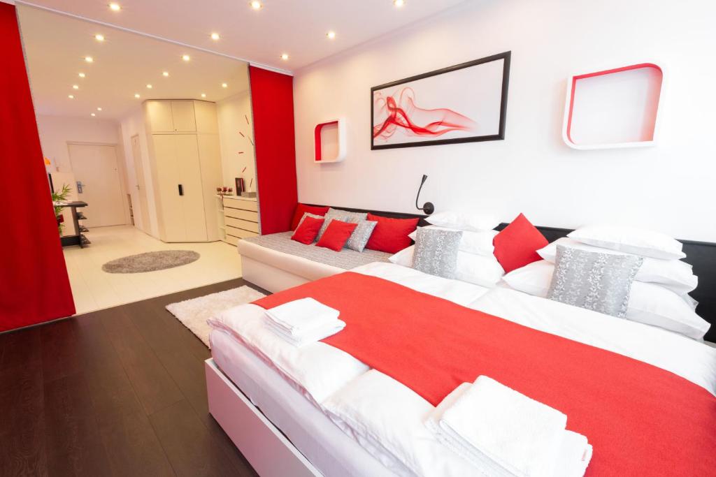 マコーにあるFlame Luxus Apartmanのベッドルーム(赤と白のベッド1台、ソファ付)