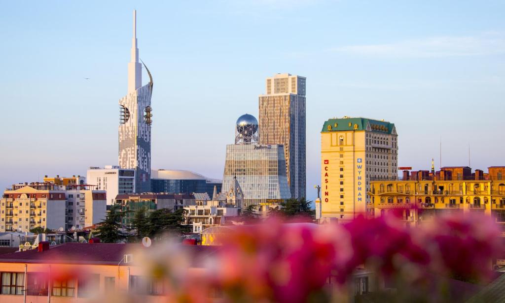 a city skyline with tall buildings and pink flowers at Luxury Room in Batumi
